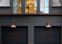 Black Painted House with Horizontal Wood Piece over Garage Doors: A Unique Design