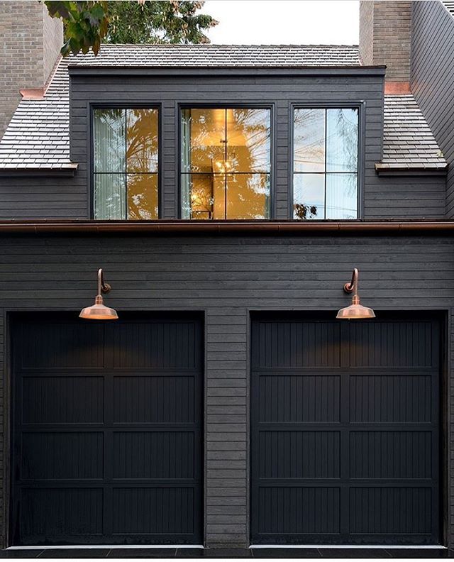 Black Painted House with Horizontal Wood Piece over Garage Doors: A Unique Design